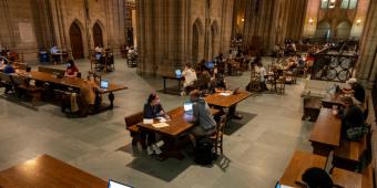 Students studying at tables in large open space. 